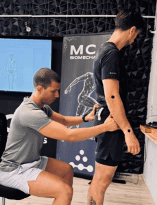 A biomechanics specialist placing motion markers on a man's hip to prepare for a gait and posture analysis.