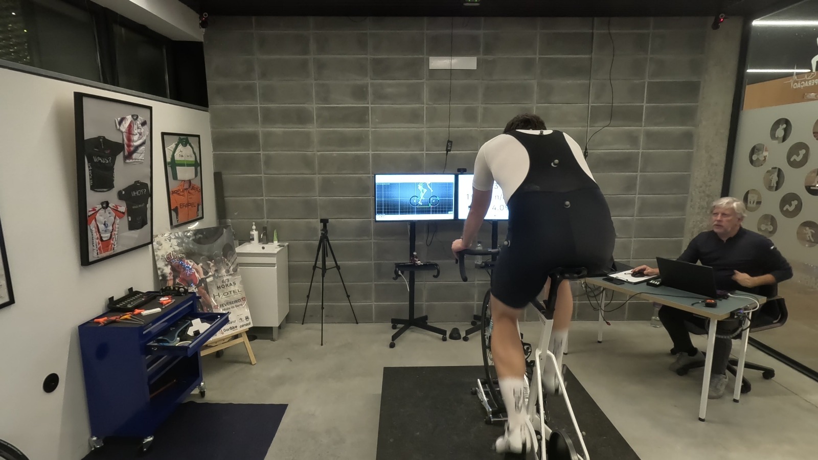 Cyclist undergoing a biomechanical analysis or professional bike fit in a specialized laboratory with motion analysis.