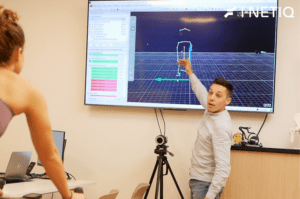 Expert applying a 3D tracking sensor to a cyclist's leg during a professional bike fit session to measure joint angles.